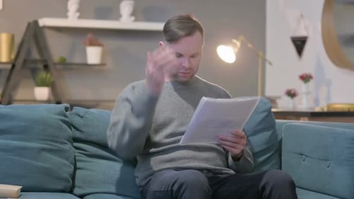 Man Reading Important Documents on the Couch