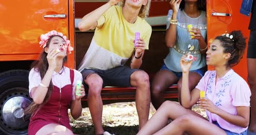 Friends Blowing Bubbles Beside Orange Van
