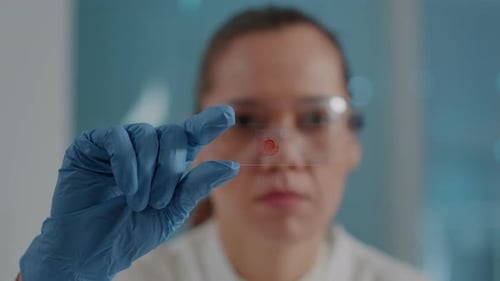 Scientist Examining Blood Sample on Slide in Lab