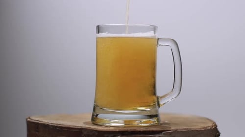 Beer Being Poured Into Mug on Wooden Surface