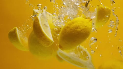 Lemons Sinking in Water on Yellow Background