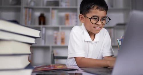 Boy Wearing Glasses Typing on Laptop at Desk