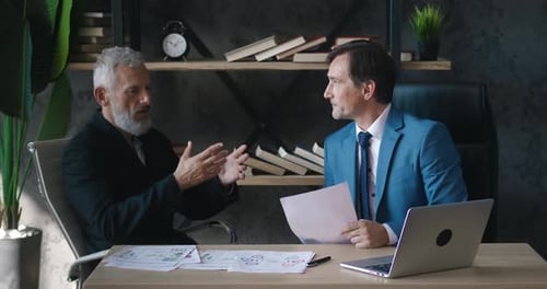 Businessmen Discussing Charts in Office Workspace