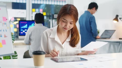 Asiatische junge Geschäftsfrau, die intelligent schreibt und einen Stift mit einem digitalen Tablet-Computer verwendet.