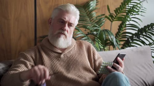 Senior Man Checking Medication with Smartphone Indoors