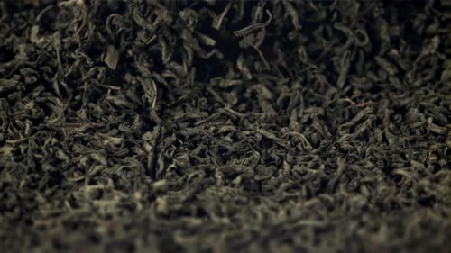 Dry Tea Leaves Falling into Pile Close Up