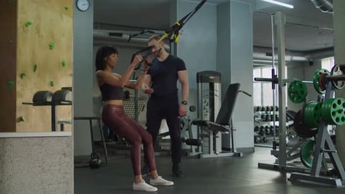 Female Exercising with Trx Fitness Straps at Gym