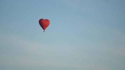 Red Heart Balloon Flying in Blue Sky