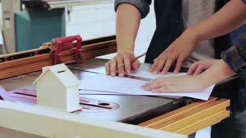 Close up of Two Carpenter workers designing construction for built-in furniture project in workshop