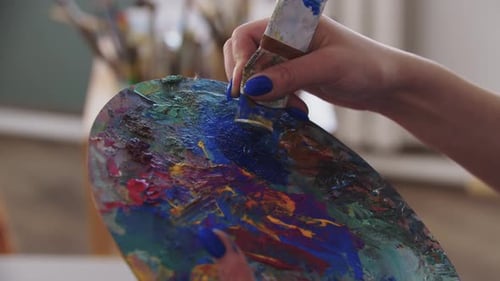 Eine Künstlerin mischt blaue Farben auf der Palette
