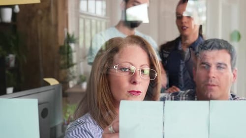 Business Team Brainstorming with Sticky Notes on Glass