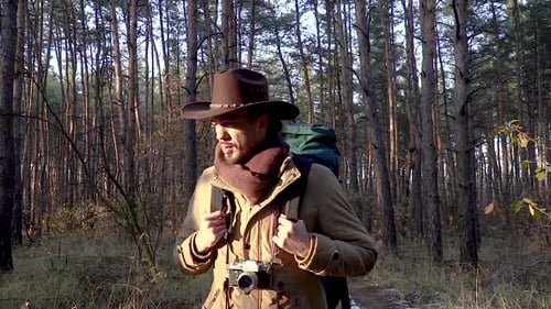 A Man with Camera Walks Along a Trail in the Forest