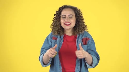 Smiling Woman Gives Thumbs Up on Yellow Background