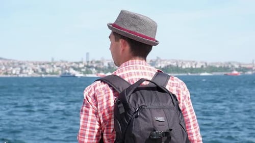 Man with Backpack near City and Ocean
