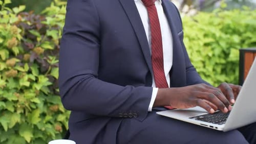 Man in Suit Working on Laptop Outdoors