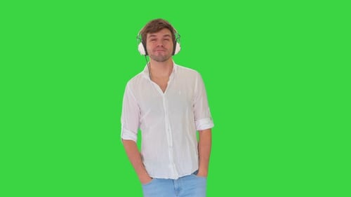 Casual Young Man in Headphones Listening To Music and Enjoying It Closing His Eyes on a Green Screen