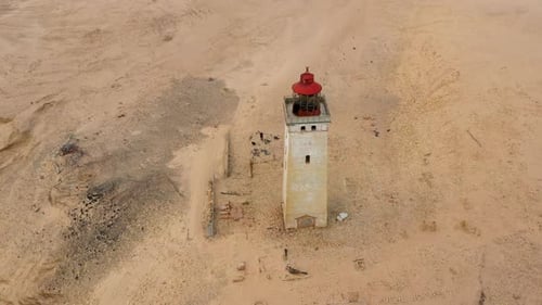 Lighthouse Amidst Majestic Sand Dunes Next to Ocean
