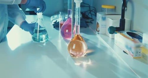 Scientist Adds Liquid to Flasks in Laboratory
