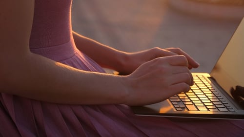 Woman Typing on Laptop During Sunset