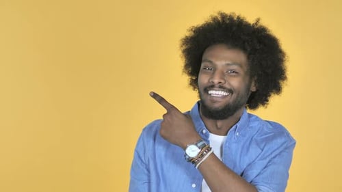 Smiling Man Pointing to the Side on Yellow