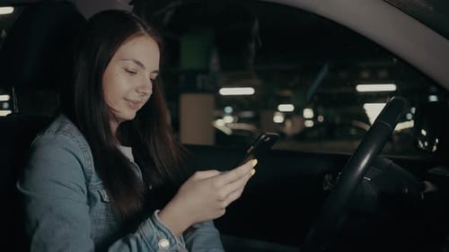 Woman Uses an Application on His Phone While Sitting in the Car in the Parking Lot