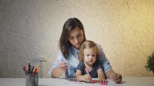 Woman and Child Drawing Together at Table Indoors
