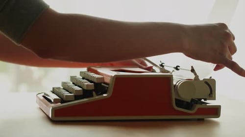 Person Typing on a Vintage Red Typewriter