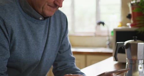 Mature Adult Uses Tablet Device in Kitchen