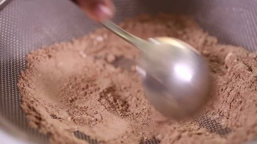 Spoon Mixing Cocoa Powder in Mesh Sieve