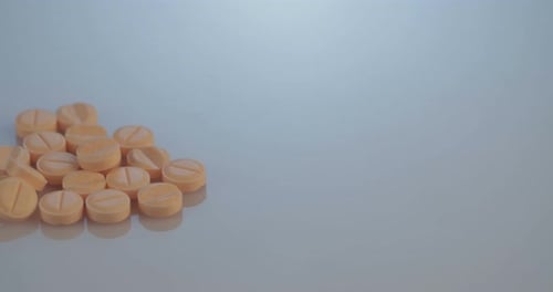 Pile of Peach Colored Medication Rolling Into Frame