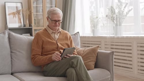 Senior Man Relaxing on Couch with Tablet