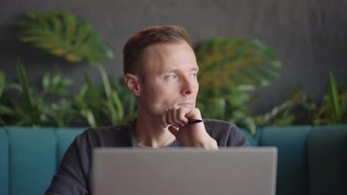 Young Adult Man Thinking with Laptop Indoors