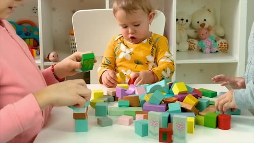 Children Playing with Colorful Building Blocks at Table