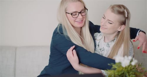 Two Blond Women Friends Embracing Affectionately Indoors