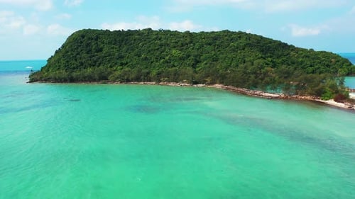 Isolated remote tropical island with lush vegetation and green trees forest surrounded by shallow tu