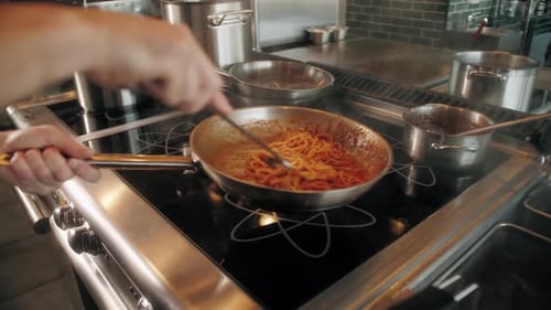 Chef Prepares Spaghetti with Red Sauce in Kitchen