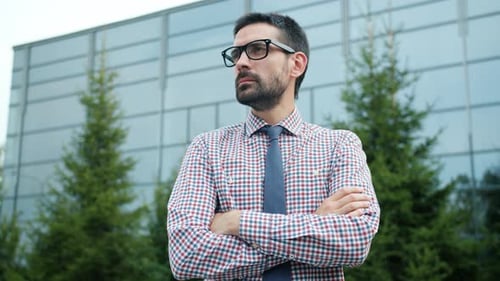 Man in Glasses Stands Confidently Outdoors