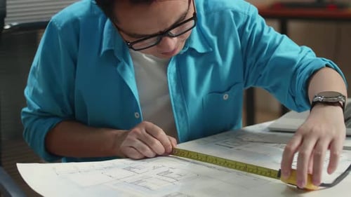 Close Up Of Asian Man Engineer With A Laptop Measuring Blueprint At The Office