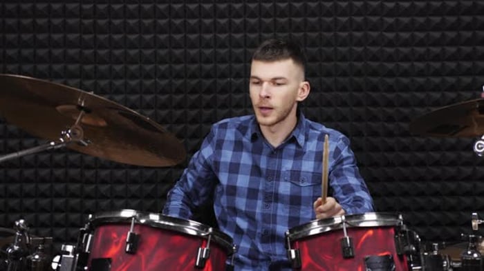 Musician playing on drum kit on stage at sound recording studio ...