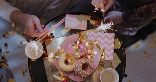 Young Adults Light Sparklers Over Donuts at Party