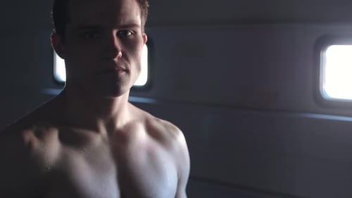 Incredible moody cinematic shot of a young attractive MMA fighter looking at the camera in slow moti