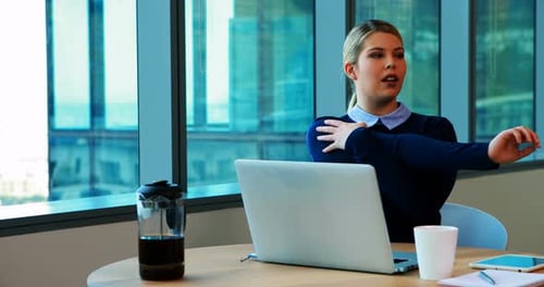 Female executive stretching her hands while working in office