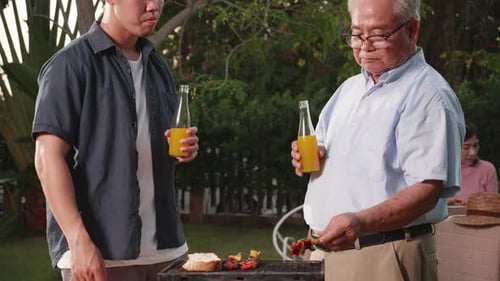 Happy Asian family having a barbecue-BBQ party together in the garden at home.