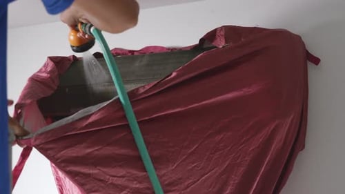 Technician using high pressure water spray are cleaning the air conditioner