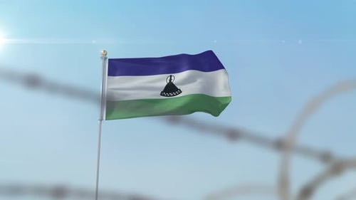 Lesotho Flag Waving Behind Barbed Wire on Clear Day