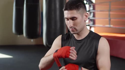 Man Wrapping Hands in Boxing Wraps Before Training