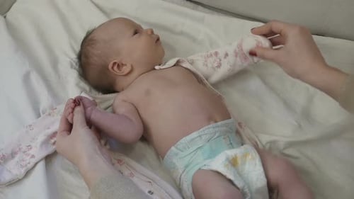 Adult Dressing a Baby in Onesie