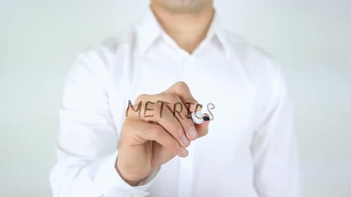 Man Writing Metrics on Clear Surface