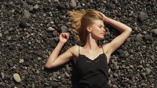 Woman Lies Relaxed on Rocky Beach, Aerial View