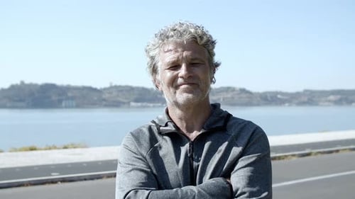 Smiling Man With Curly Hair Stands By Water